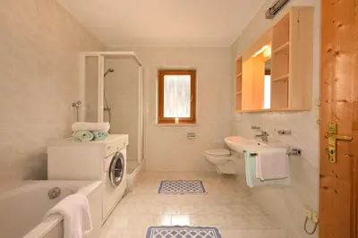 a bathroom with a tub sink and a washing machine at Obererhof in SantʼAndrea in Monte