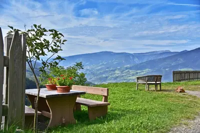 a bench and a table with flowers on top of a hill at Obererhof in SantʼAndrea in Monte