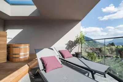 a balcony with two chairs and a view of the mountains at Vinea - Apartments in Tirolo