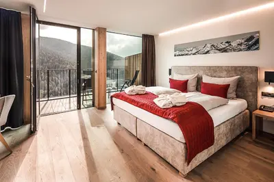 a bedroom with a large bed and a balcony at Hotel Panoramic Lotsch in Sarntal
