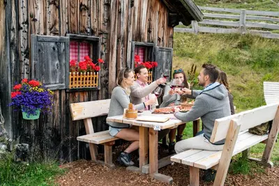 a group of people sitting at a table outside a cabin at Hotel Panoramic Lotsch in Sarntal