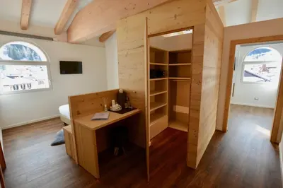 a room with a desk and a bedroom with two windows at Le Suite della nonna Teresina in Moena