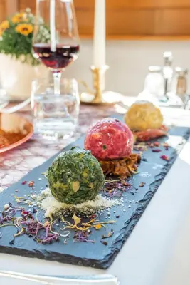 a table with a plate of food and a glass of wine at Charme Hotel Uridl in Santa Cristina in Val Gardena