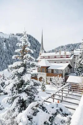 a snow covered christmas tree in front of a building at Charme Hotel Uridl in Santa Cristina in Val Gardena