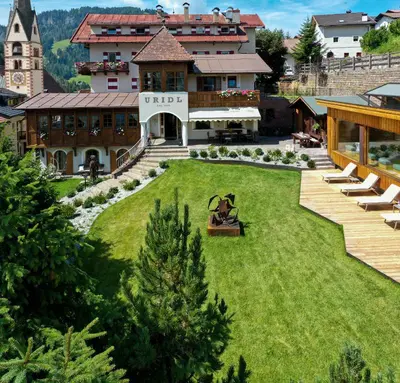a person sitting on a bench in the yard of a house at Charme Hotel Uridl in Santa Cristina in Val Gardena