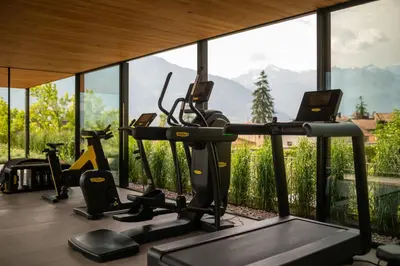 a gym with several cardio machines in front of a large window at Muchele Boutique Hotel in Postal