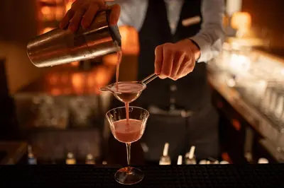 a man pouring a drink into a martini glass at Muchele Boutique Hotel in Postal