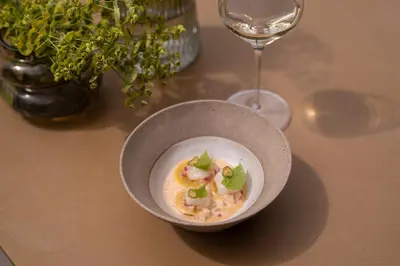 a bowl of food on a table next to a wine glass at Muchele Boutique Hotel in Postal