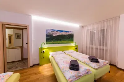 a bedroom with two beds and a painting on the wall at Casa Trettel in Tesero
