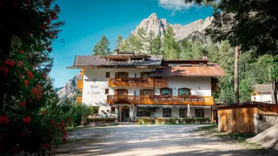 a large building with a mountain in the background at Hotel il Cardo in San Vito di Cadore
