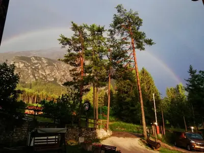 a rainbow in the sky over a park with a tree at Hotel il Cardo in San Vito di Cadore