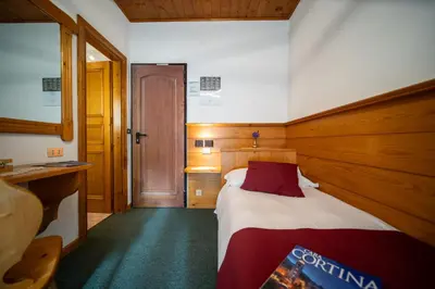 a small bedroom with a bed and a desk at Hotel il Cardo in San Vito di Cadore