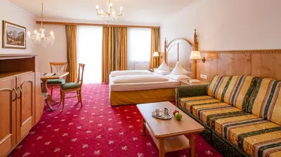 a hotel room with a bed and a couch at The Oswald Grand Hotel in Selva di Val Gardena
