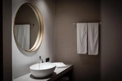 a bathroom with a sink and a mirror and towels at The Oswald Grand Hotel in Selva di Val Gardena