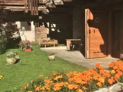 a garden with orange flowers and a wooden door at Chalet nel cuore delle Dolomiti in Falcade