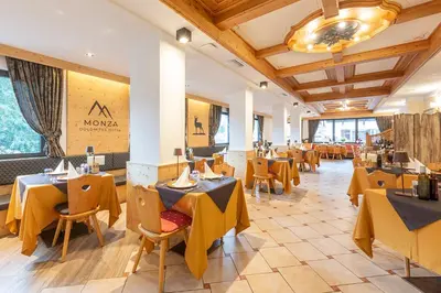a building with a patio with tables and chairs at Monza Dolomites Hotel in Moena