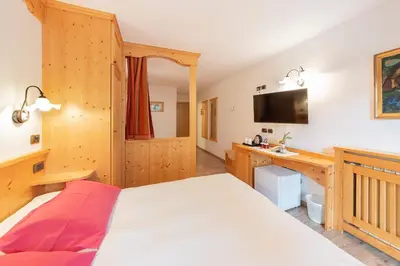 a bed with white sheets and pillows at Monza Dolomites Hotel in Moena