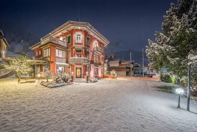 a large house in the snow at night at Hotel Luis in Fiera di Primiero