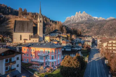 a town in the mountains with a church and a street at Hotel Luis in Fiera di Primiero