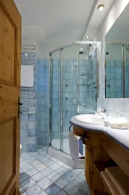 a green tiled bathroom with two sinks and a bath tub at Hotel Cortina in Cortina dʼAmpezzo