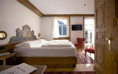 a bedroom with a bed and a chair and a table at Hotel Cortina in Cortina dʼAmpezzo