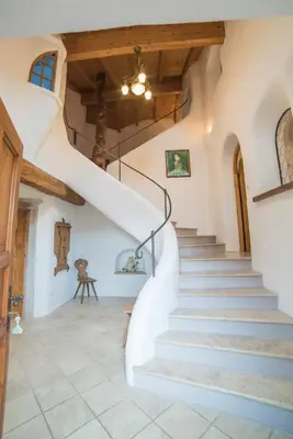 a winding staircase in a house with a wooden ceiling at Jagerhof in Caldaro