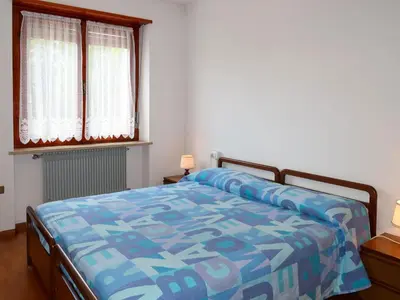 a bedroom with a bed with a blue comforter and two windows at Apartment Pancheri by Interhome in Coredo