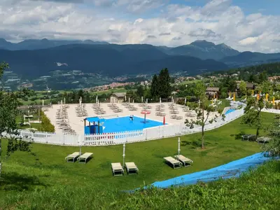 a large swimming pool in a park with lounge chairs at Apartment Pancheri by Interhome in Coredo