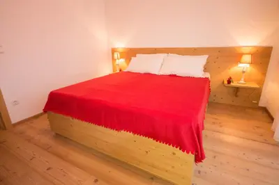 a bedroom with a bed with a red blanket on it at Aurturist Valdaora Roulette in Valdaora