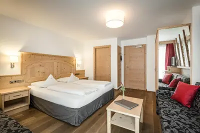 a hotel room with a large bed and a couch at Hotel Digon in Ortisei