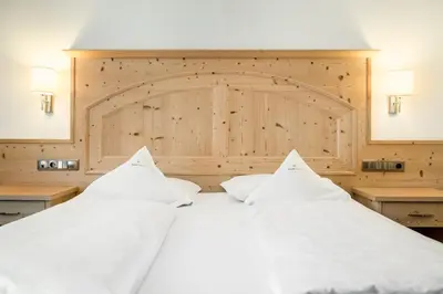 a bedroom with a large white bed with two pillows at Hotel Digon in Ortisei