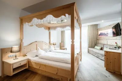 a bedroom with a canopy bed and a couch at Hotel Digon in Ortisei
