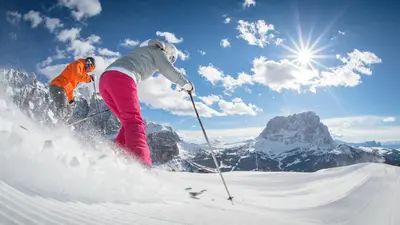 two people are skiing down a snow covered mountain at Spaces Hotel in San Vigilio Di Marebbe