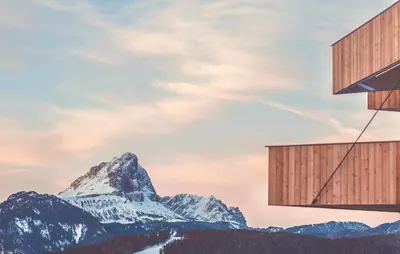 a building with a mountain in the background at Spaces Hotel in San Vigilio Di Marebbe