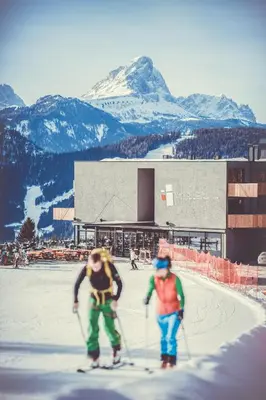 two people on skis in the snow in front of a building at Spaces Hotel in San Vigilio Di Marebbe