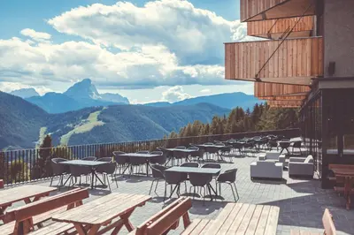 a patio with tables and chairs and mountains in the background at Spaces Hotel in San Vigilio Di Marebbe