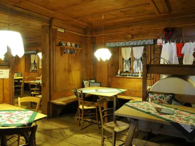 a restaurant with wooden walls and tables and chairs at Hotel Belvedere wellness in Falcade