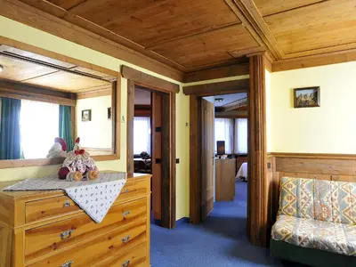 a bedroom with a wooden ceiling and a dresser with stuffed animals at Hotel Belvedere wellness in Falcade
