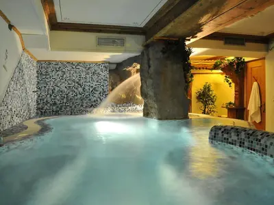 a pool of water with a waterfall in a room at Hotel Belvedere wellness in Falcade