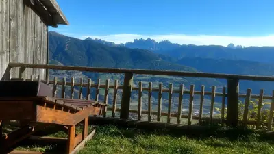 a bench in front of a fence with mountains in the background at Masitterhof in Bressanone
