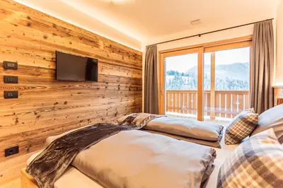 two beds in a room with a wall of wood at Apartments Milanhof in Ortisei