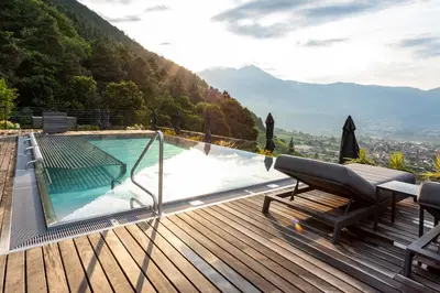 a swimming pool on a wooden deck with a view at Avidea - Adults Only in Lagundo