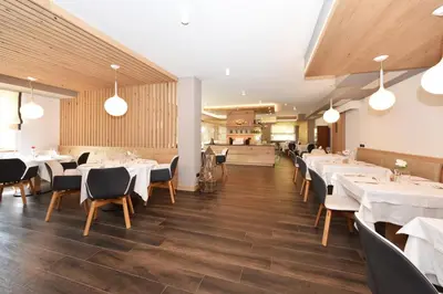 a dining room with white tables and chairs at X Alp Hotel in Pozza di Fassa