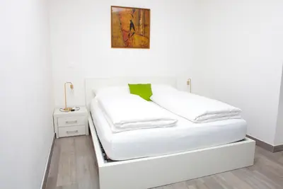 a bed with white sheets and a picture on the wall at Loft 82 Apartments in Bolzano