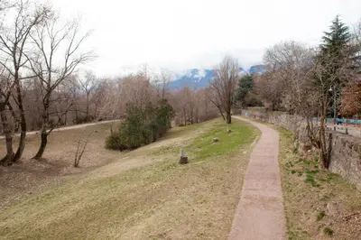 a path in a park with trees and a wall at Loft 82 Apartments in Bolzano