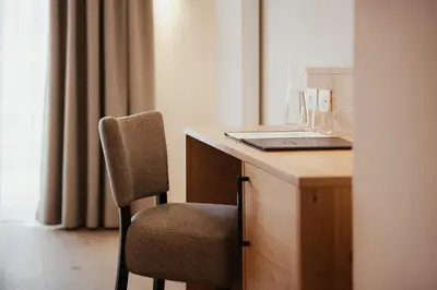 a chair sitting next to a desk with a laptop at Hotel Diamant in San Cassiano