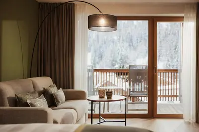 a living room with a couch and a sliding glass door at Hotel Diamant in San Cassiano