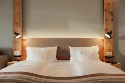 a large bed with white sheets and pillows at Hotel Diamant in San Cassiano