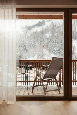 a chair sitting on a porch with a window at Hotel Diamant in San Cassiano