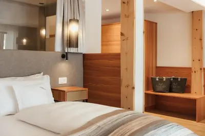 a bedroom with a white bed and wooden walls at Hotel Diamant in San Cassiano